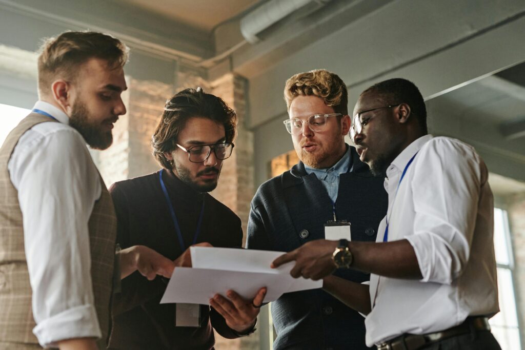 Four professionals engaged in a collaborative meeting, examining documents in an office.